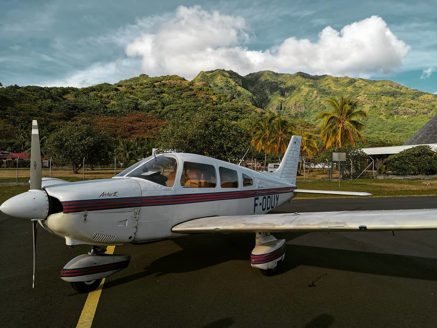 Un petit avion à trois places sur une piste au pieds de montagnes tropicales