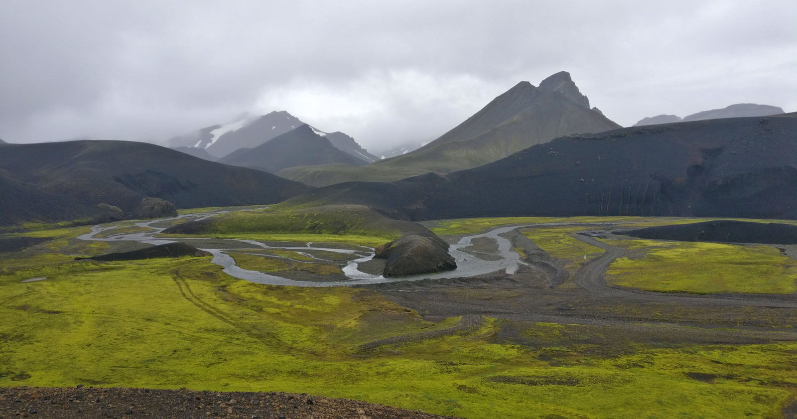 Les hautes terres d'Islande, avec le vert de la mousse de la plaine, et les montagnes noires perdues dans les nuages.